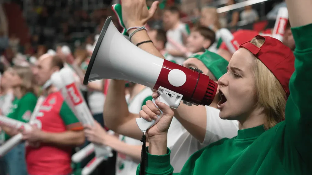 Hokejová fanynka na utkání mluví do amplionu