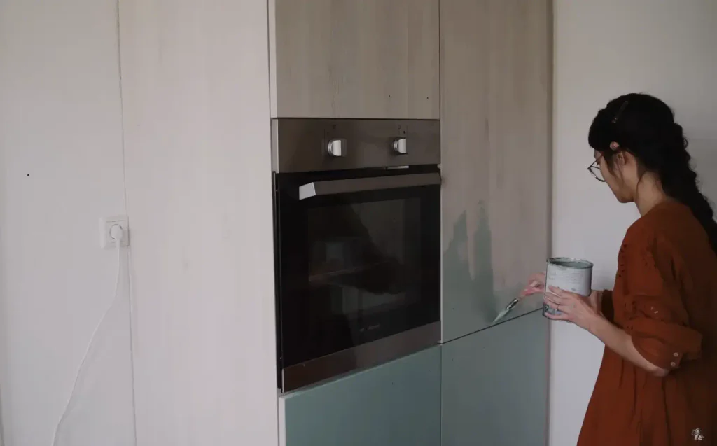 Žena natírá kuchyňské skříňky