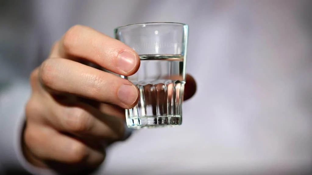 Ruka s panákem vodky