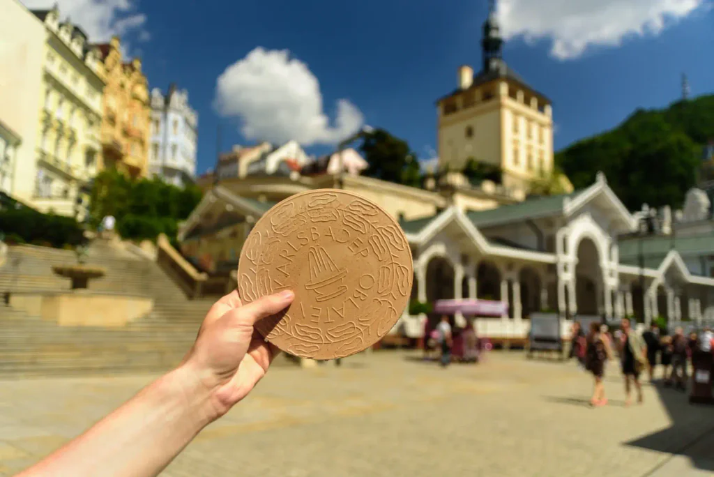 Ruka, nejspíše mladé ženy, drží před kamerou lázeňský oplatek.
