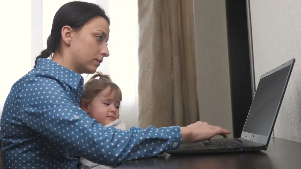 Matka pracuje u počítače, zatímco se stará o dceru