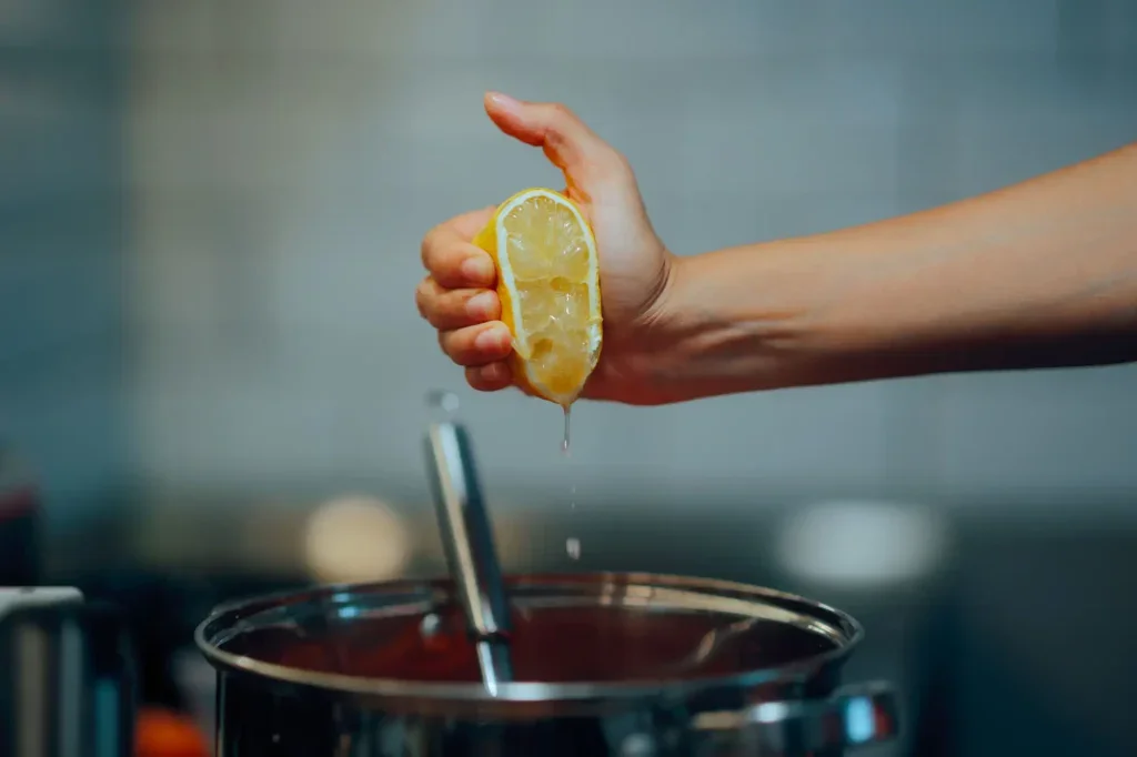 žena přidává citronovou šťávu do hrnce