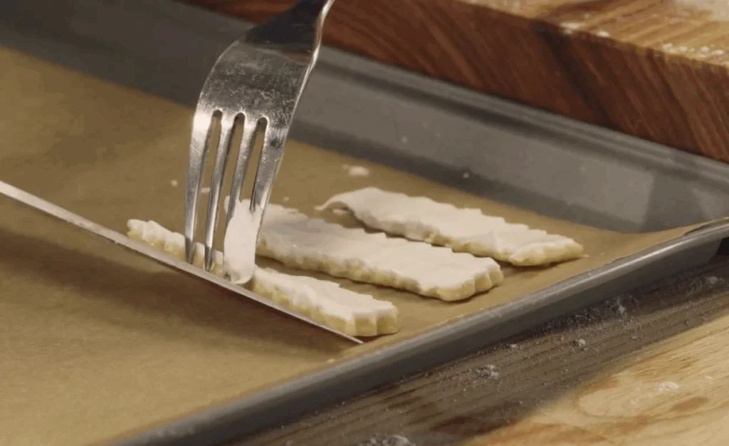 Pomocí vidličky a nože přeneseme na plech s pečícím papírem.