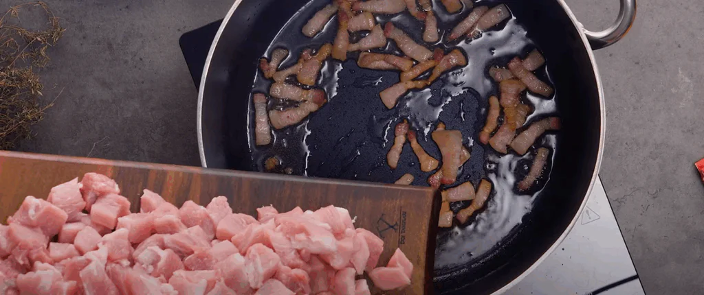 Na tuku orestujeme slaninu a přidáme nakrájené maso.