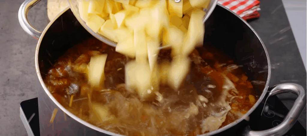 Přidáme drobně nakrájené papriky a brambory na kostky.