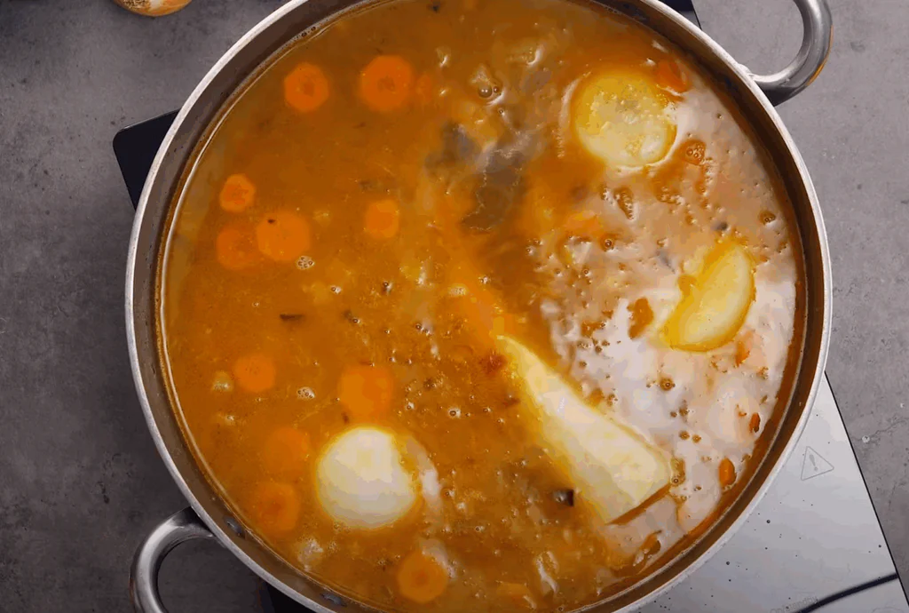 Přidáme bílou cibuli a zbytek kořenové zeleniny vcelku a zalijeme vodou.
