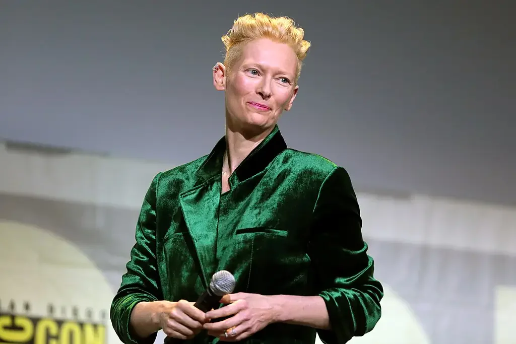 Tilda Swinton v zeleném sametovém saku drží mikrofon na filmové akci