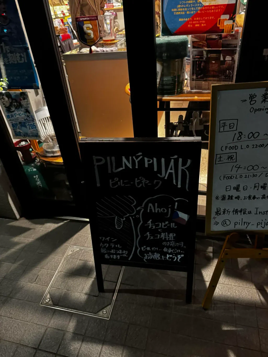 Vchod do restaurace Pilný piják. Vidět jde cedule s názvem a s českými i japonskými slovy.