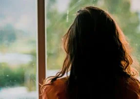 Žena se dívá z okna
