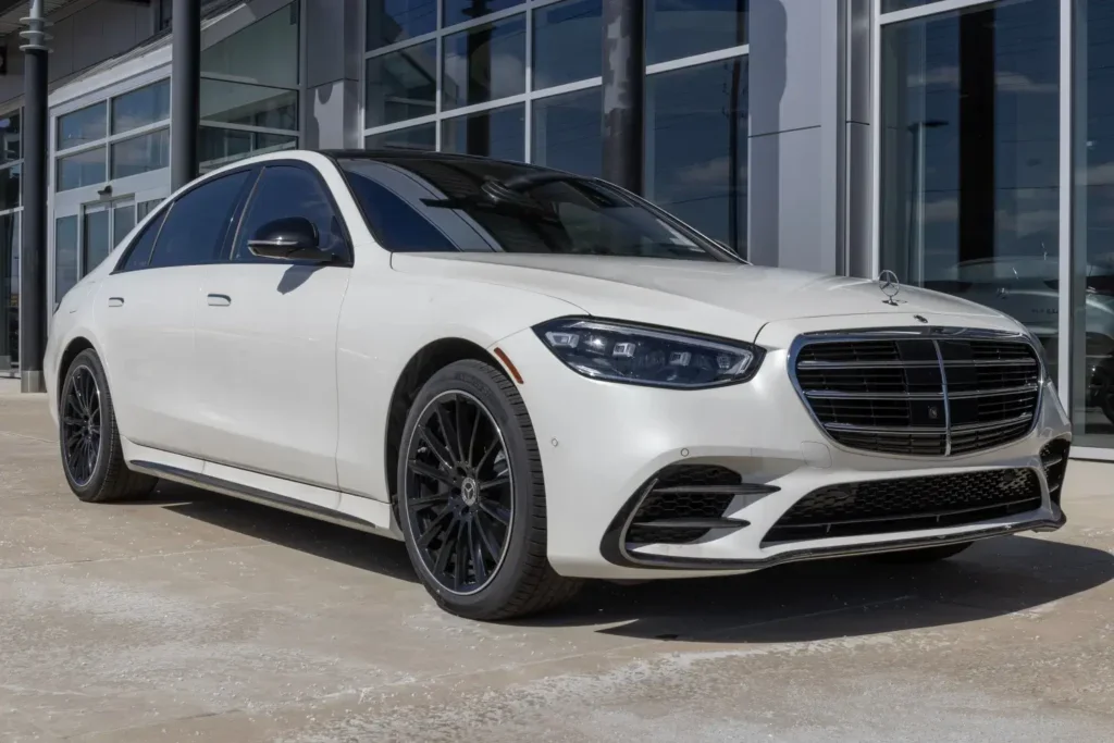 Bílý Mercedes-Benz třídy S zaparkovaný před showroomem