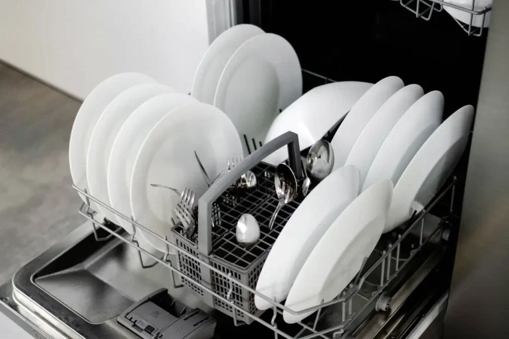 Detail spodního koše myčky se srovnanými talíři a příbory