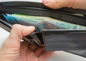 Ruce drží peněženku s bankovkami