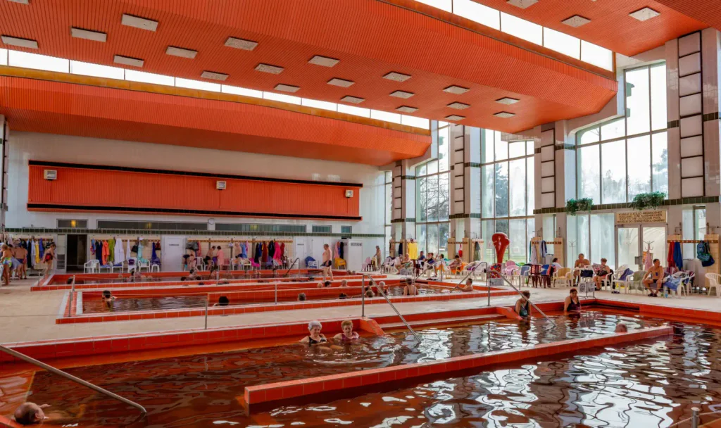 Vnitřní komplex lázní Hajdúszoboszló. Vidět jsou bazény a lidé, kteří se v nich koupají.