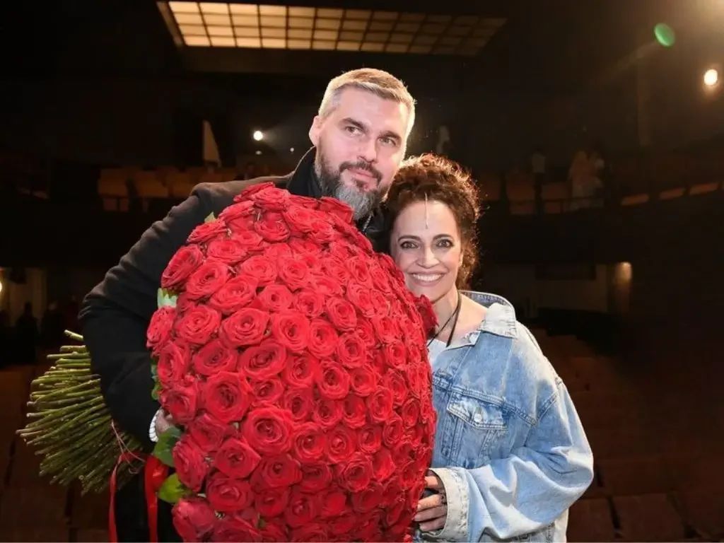Lucie Bílá se usmívá po boku Radka Filipiho, který drží obrovskou kytici červených růží