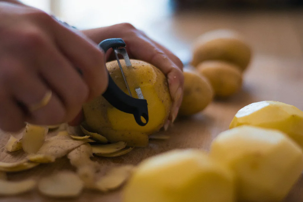 A person peeling a lemon with a pair of scissors