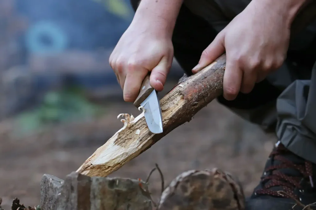 muž pomocí nože osekává dřevo